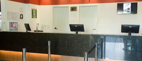 A reception desk at a hotel with a sign reading "Stop Inn Bello Horizonte".