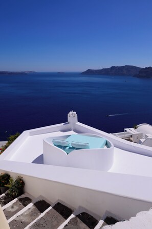 A white infinity pool with a view of the sea and distant hills. -  Cave Agapi Oia (Santorini)