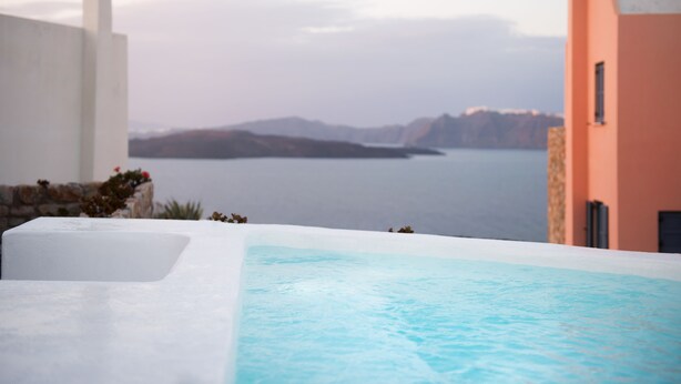 Un área de piscina con vista al mar y montañas al lejano.