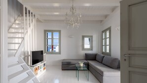 Una sala de estar moderna con una escalera, un sofá, una mesa de centro de vidrio y un televisor.