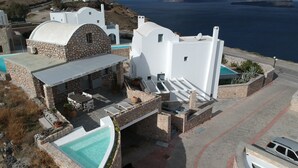 Un edificio blanco de fachada de piedra, una piscina y vistas al mar.