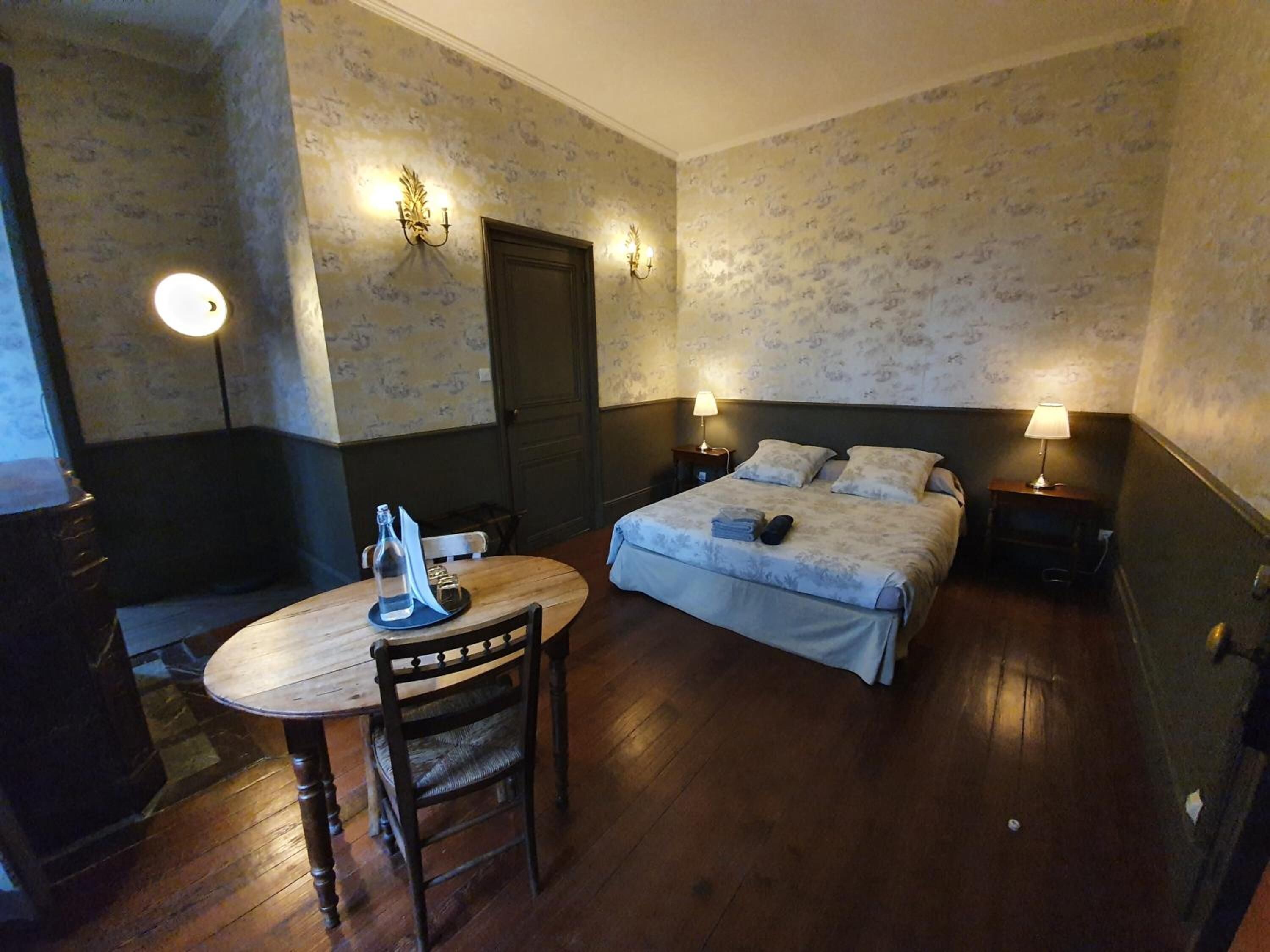A room with a bed, a table with a chair, and two bedside lamps.
