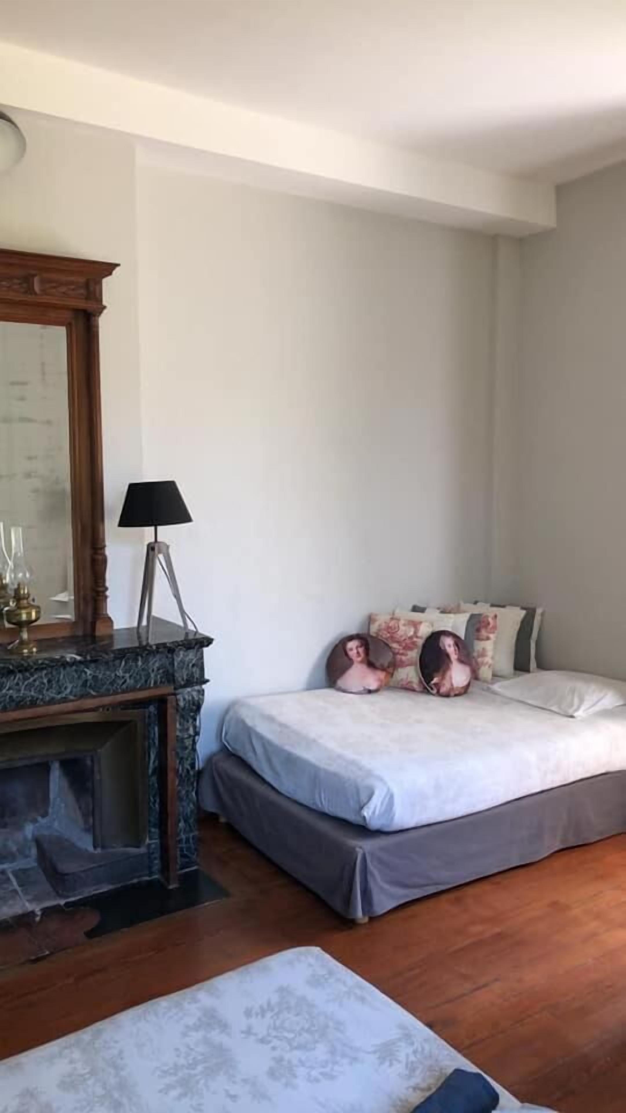 Ein Schlafzimmer mit Bett, Nachttisch, Lampe und Kamin.