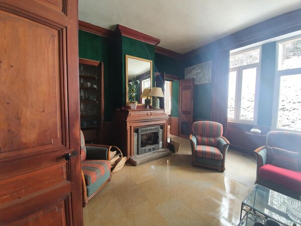 Una habitación tradicional con chimenea, un espejo y una estantería.