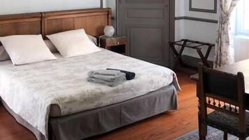 Een slaapkamer met een houten bed, nachtkastje, stoel en een deur.