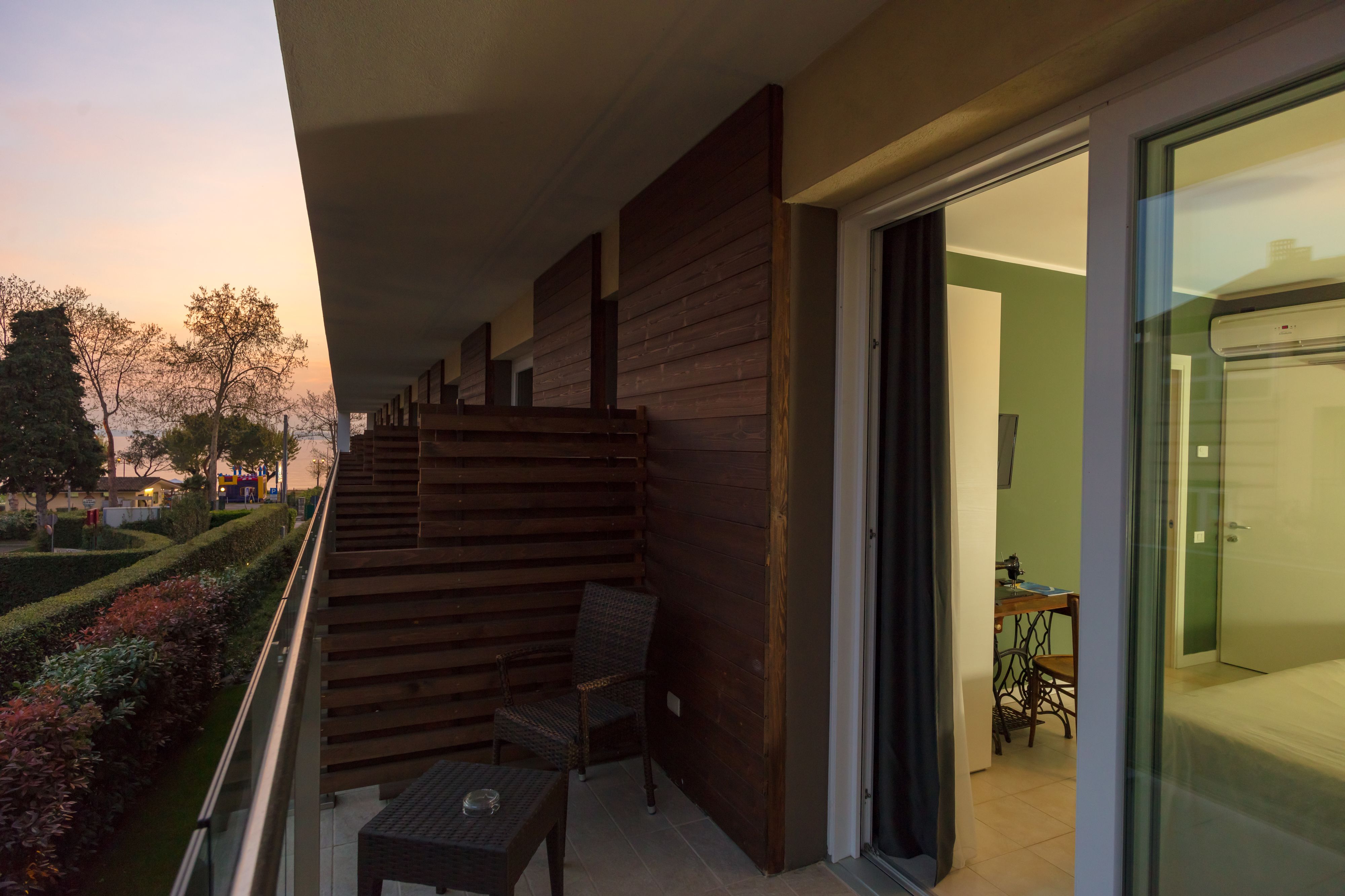 A balcony with a wooden slatted wall, a small table, and two chairs.