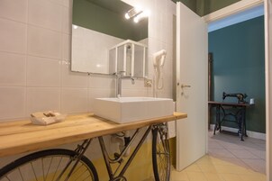 Un baño con tocador de madera, un lavamanos blanco, un espejo y un secador de pelo.