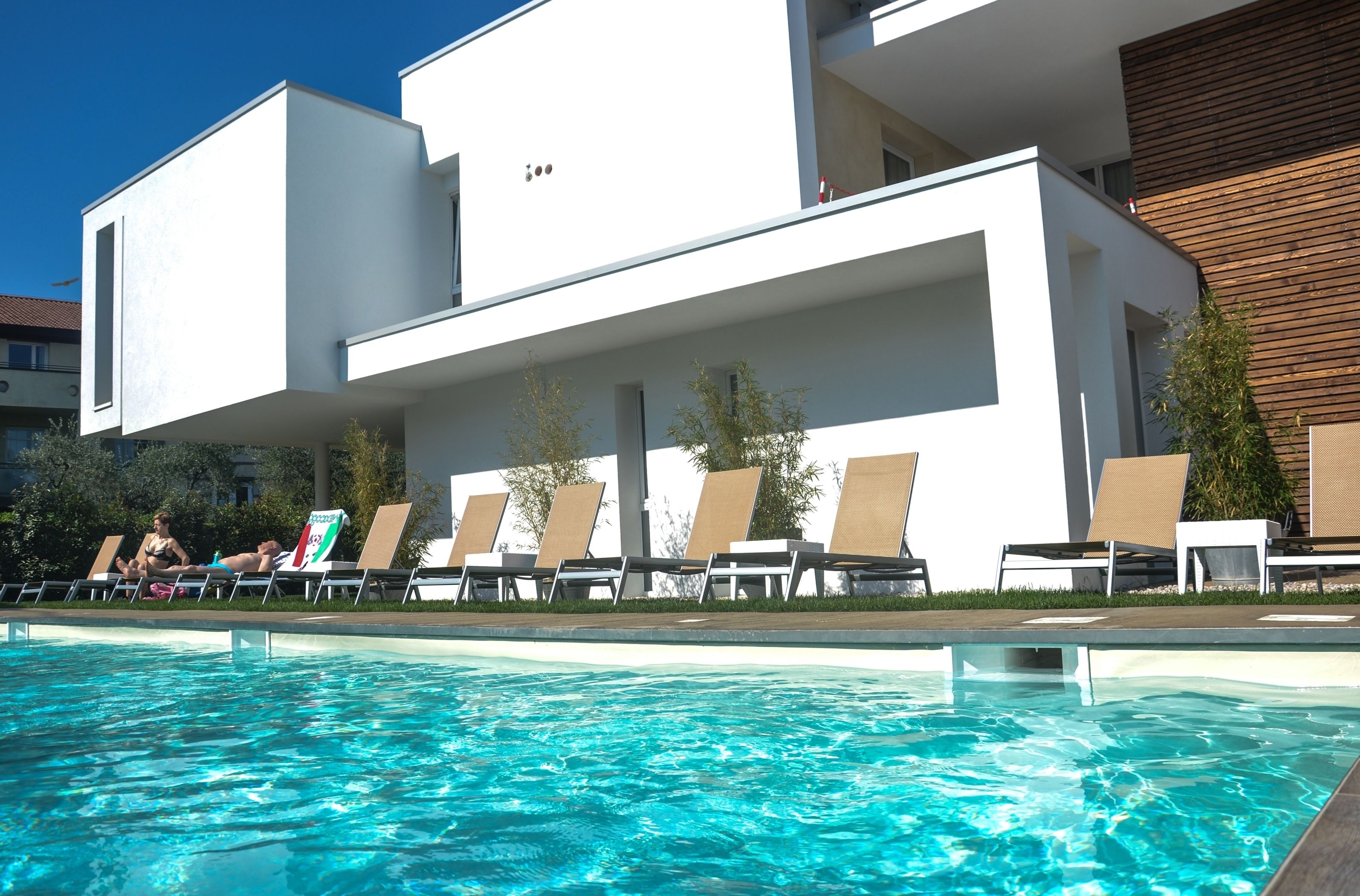 Un edificio moderno con piscina y sillones de descanso.
