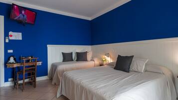 Ein Hotelzimmer mit zwei Betten, einem Schreibtisch und einem an der Wand befestigten Fernseher.