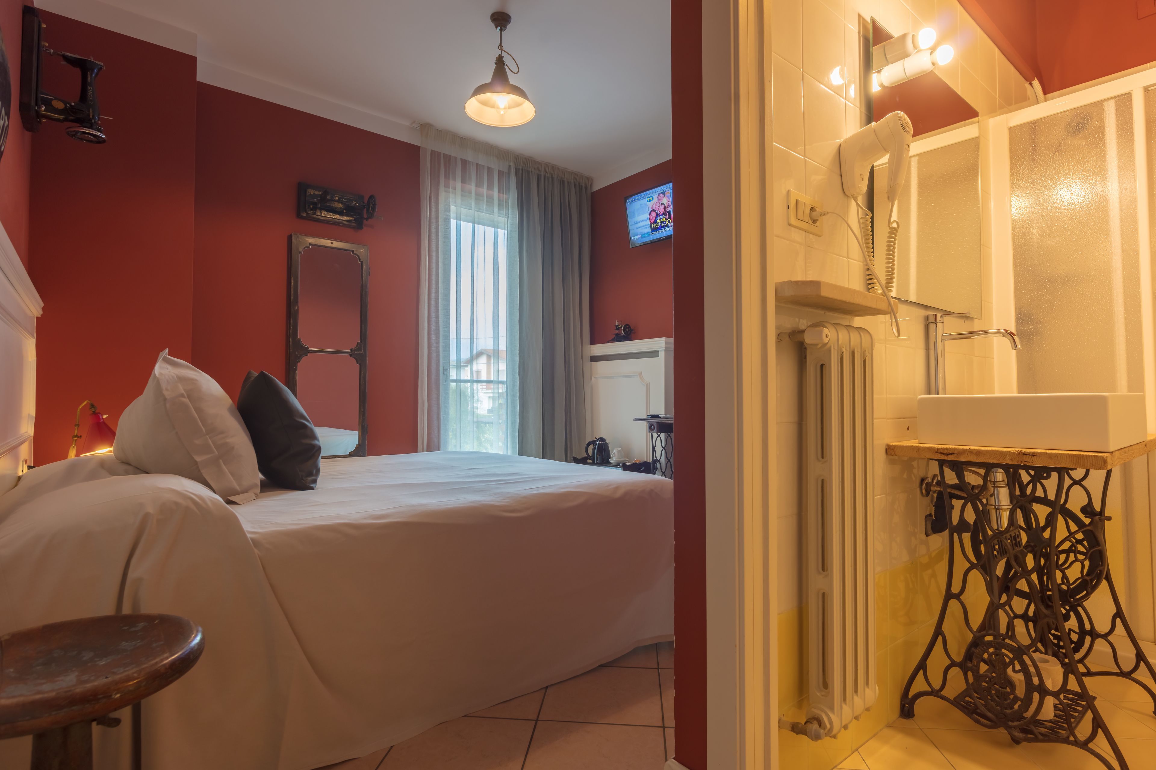 Une chambre d’hôtel avec un lit, une petite table, un radiateur et un téléviseur fixé au mur.