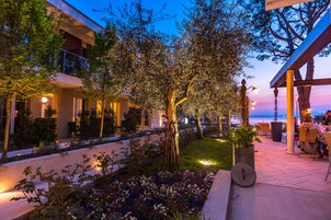 Un patio al aire libre con asientos, un árbol y vista al mar.