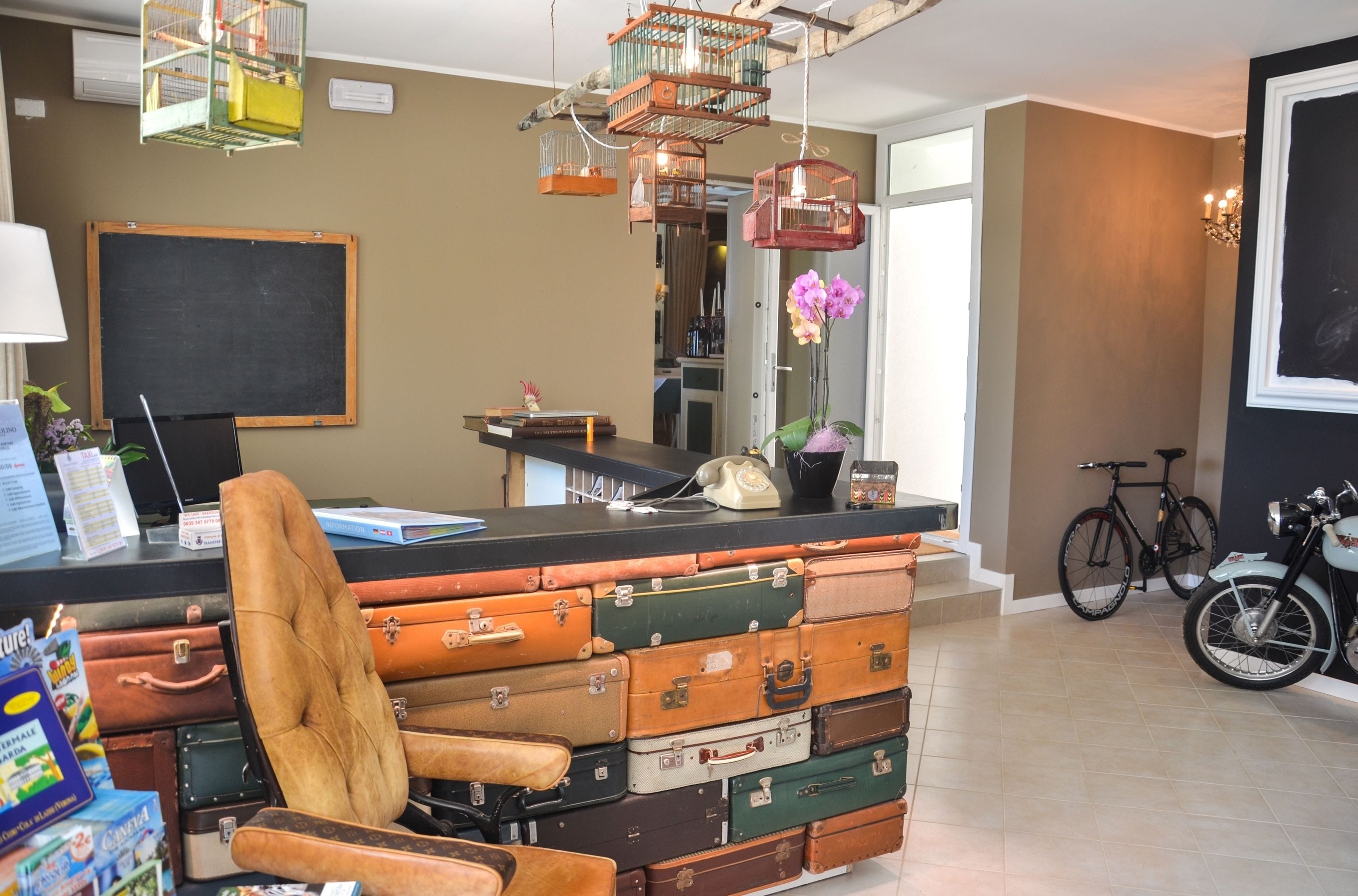 Ein Zimmer mit Barbereich, ausgestattet mit einer Sammlung alter Koffer, einem Fahrrad und einem Motorrad.