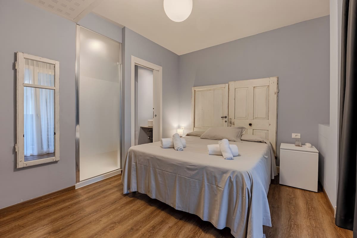 A bedroom with a bed, bedside tables, a wardrobe, and a window with curtains.