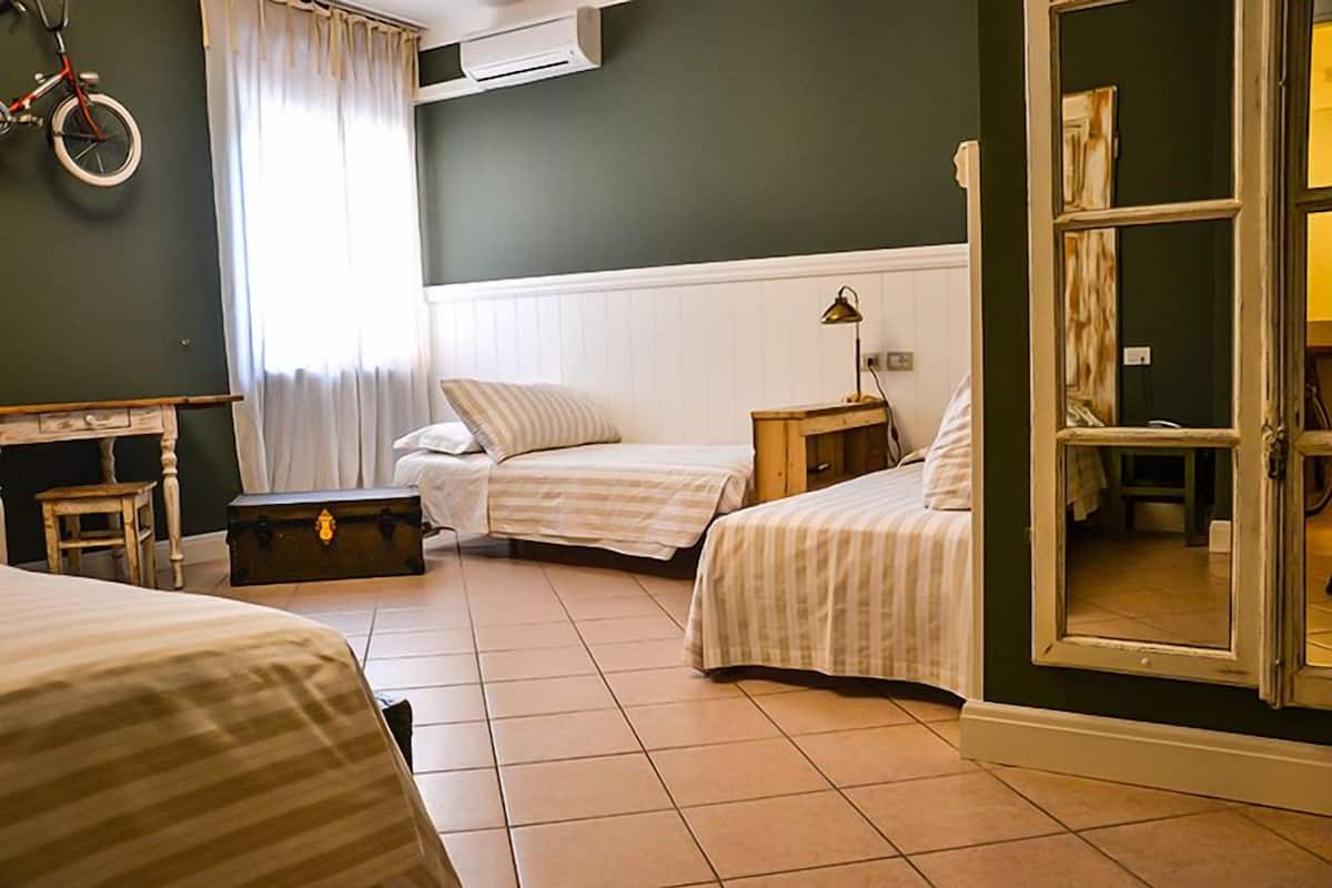 A room with two beds, a bicycle, a suitcase, and a lamp.