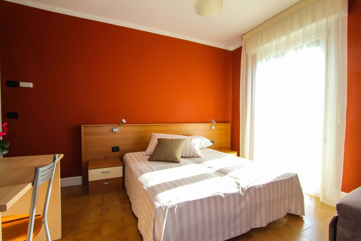 A hotel room with a bed, a desk, and a chair.