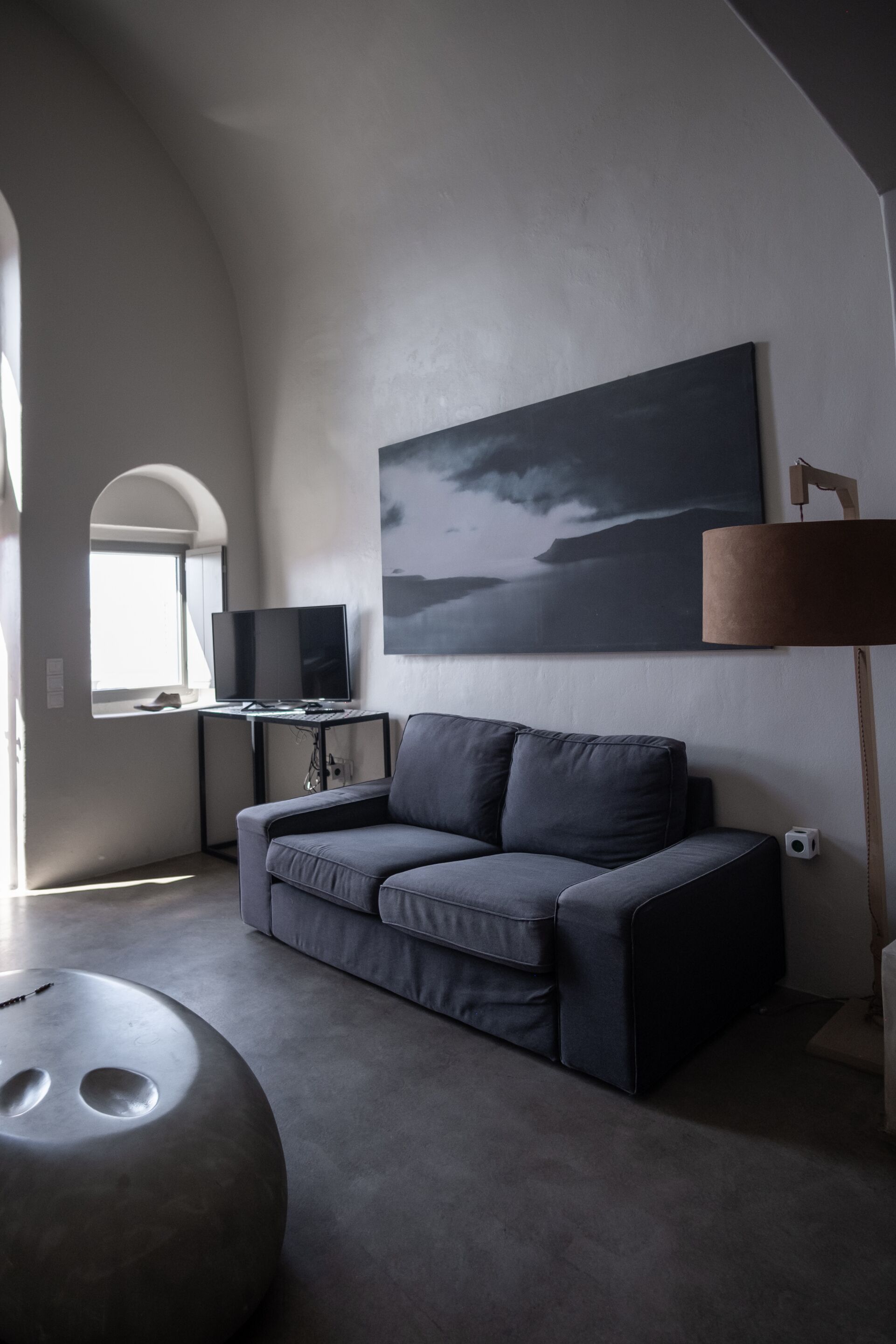 Una sala de estar moderna con un sofá gris, un televisor de pantalla plana, un cuadro y una lámpara.