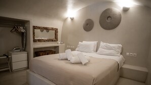 Un dormitorio con una cama grande, una mesita de noche, un aparador, un espejo y una lámpara de pared.