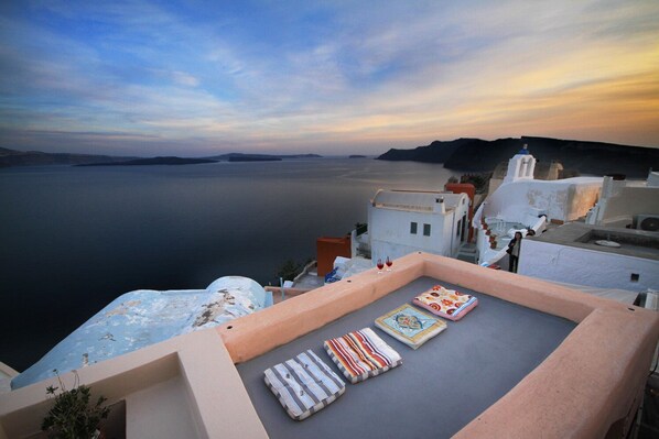 A rooftop terrace with a view of the sea and a sunset. - Alafouzou Cave Loft (Santorini)