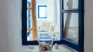 Una habitación con un ventanal grande, una cama y una pequeña mesa con piedras.