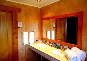 A bathroom with two sinks, a large mirror, wooden cabinets, and a towel rack. - Hosteria Patagon (Villa La Angostura)