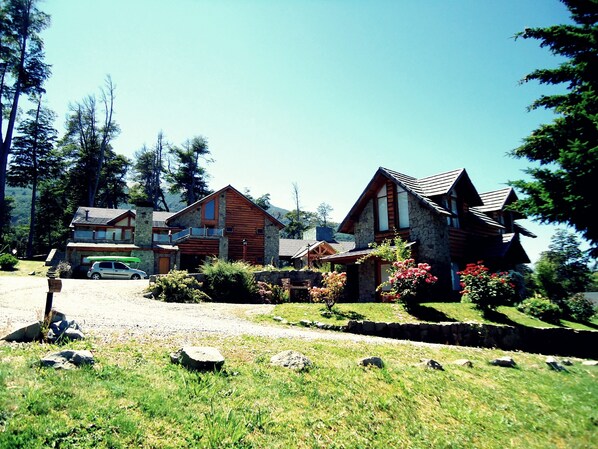 A two-story stone house with a wooden deck and a stone chimney. - Hosteria Patagon (Villa La Angostura)