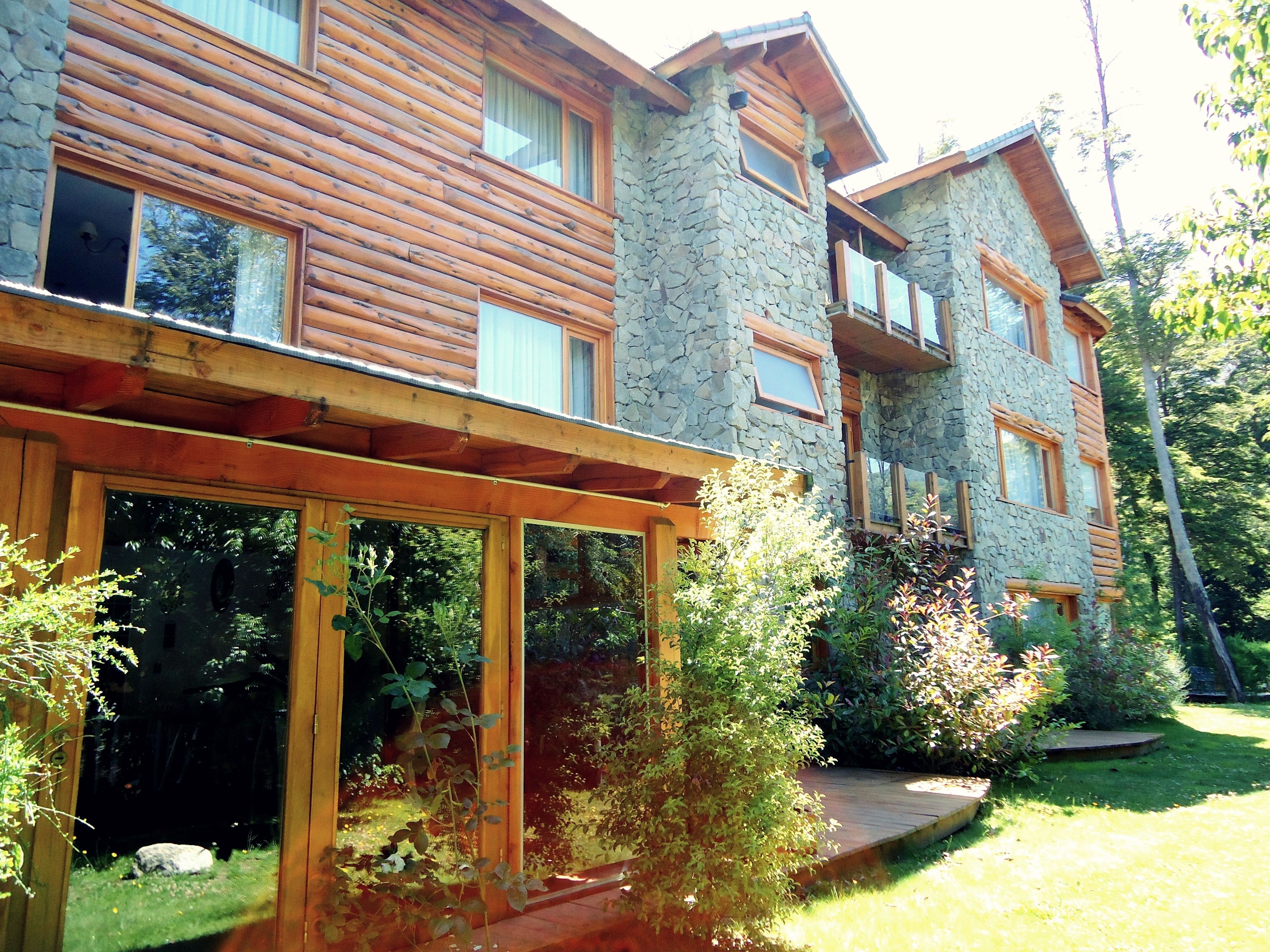 Une cabane en rondins à deux étages, avec des murs en pierre et des balcons en bois.