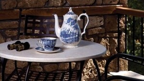 A table with a teapot and a cup, set against a stone wall.