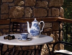 A table with a teapot and a cup, set against a stone wall.