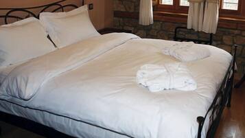 A neatly made bed with white linens and two folded towels on the footboard.
