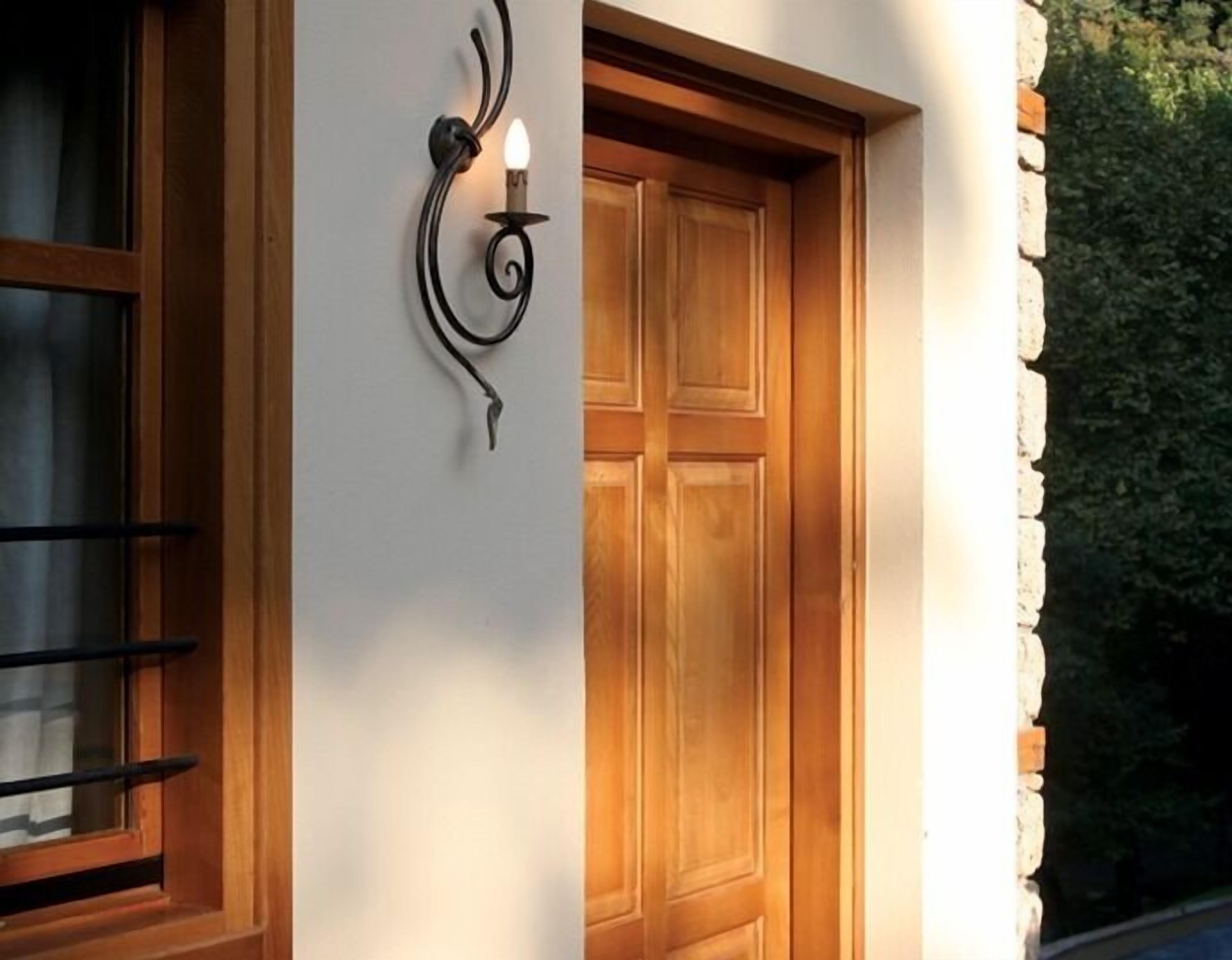 A wooden door with a metal handle and a wall-mounted light fixture.