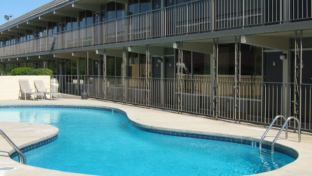 A hotel with a swimming pool, outdoor seating, and a covered balcony area. - Alcoa Inn (Alcoa)