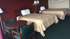 A hotel room with two beds, a round table, and green upholstered chairs. - Alcoa Inn (Alcoa)