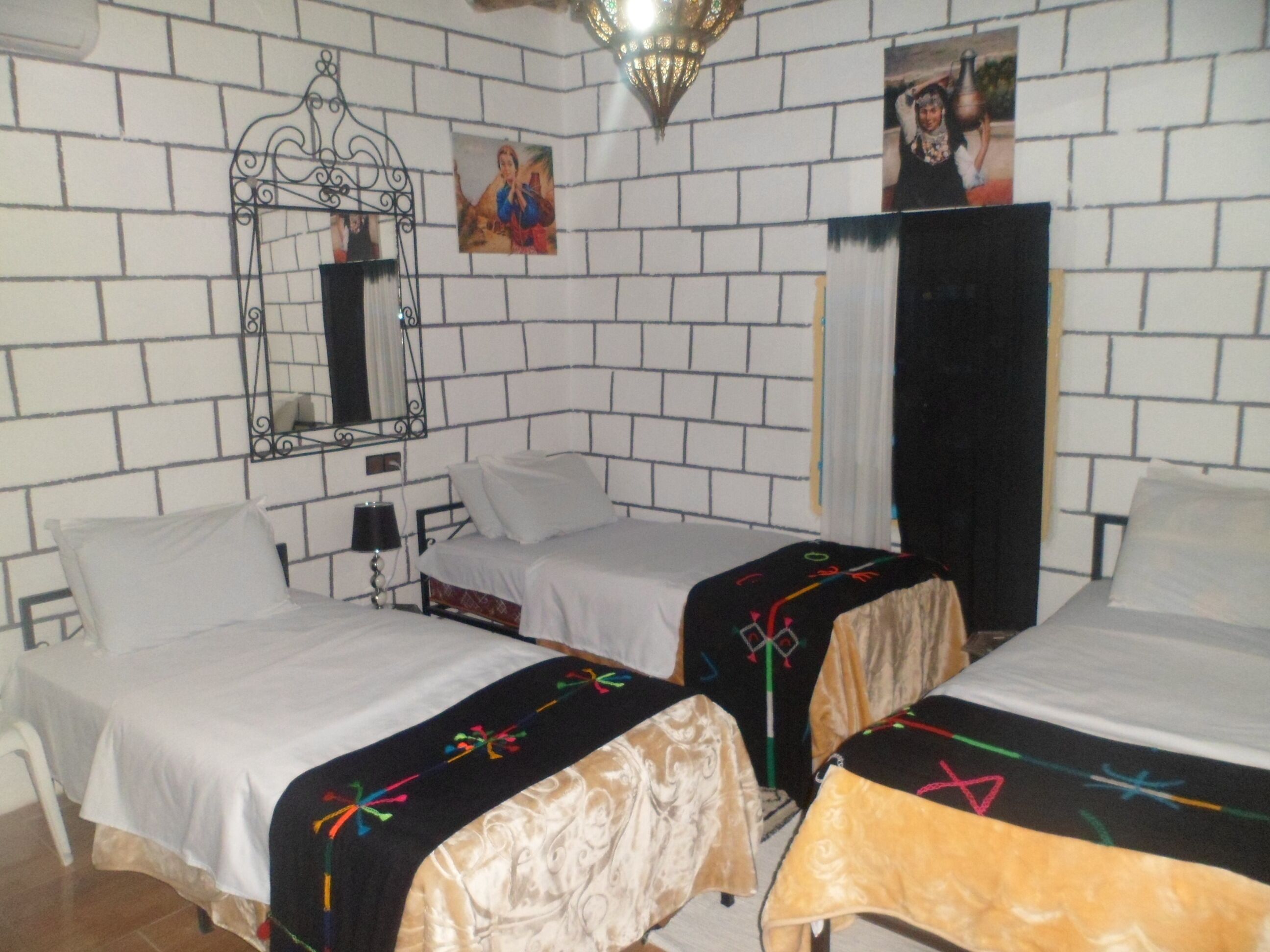 Una habitación con dos camas, un espejo y una pared decorada con cuadros.