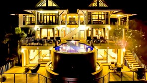 Un hotel de dos pisos con piscina central, asientos al aire libre y una escalera que conecta los niveles.