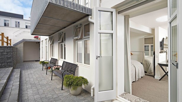 A residential property with a paved patio, a bench, a potted plant, and a bed with a patterned rug. - Ice Apartments Reykjavik by Heimaleiga (Reykjavik)