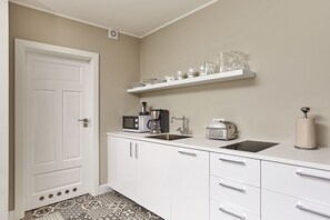 A kitchen with white cabinets, a microwave, a toaster, a sink, and a shelf with glassware. - Ice Apartments Reykjavik by Heimaleiga (Reykjavik)