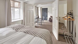 A hotel room with a bed, a desk, and a chair. There is a coat rack with hangers and a mirror. - Ice Apartments Reykjavik by Heimaleiga (Reykjavik)