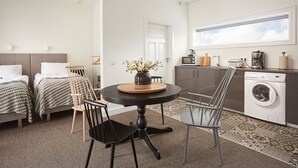 A compact hotel room with two beds, a dining table with chairs, a washing machine, and a large window. - Ice Apartments Reykjavik by Heimaleiga (Reykjavik)