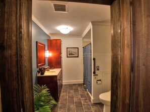 Un baño con tocador de madera, lavamanos, inodoro y cortina de ducha.