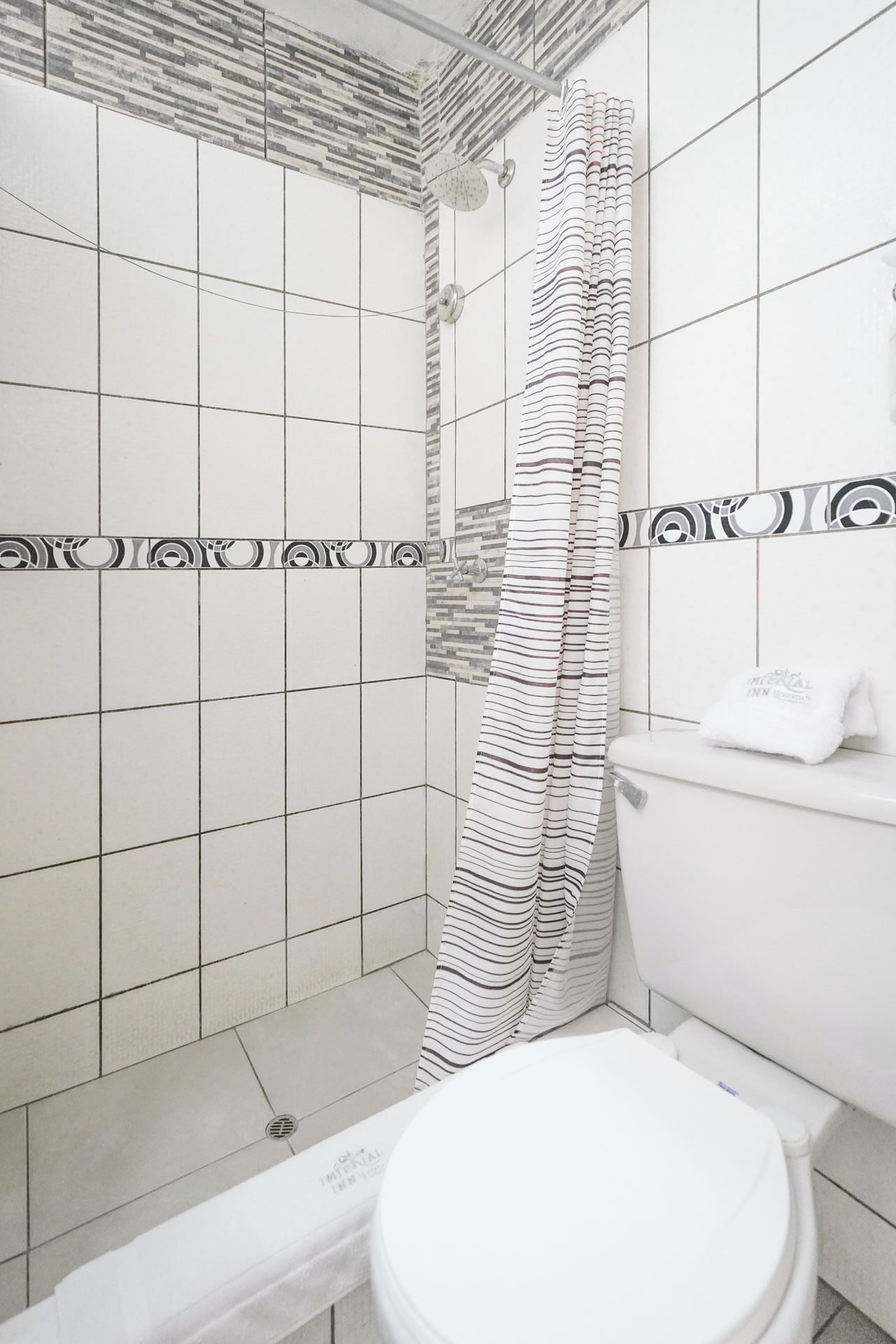 A bathroom with a shower, toilet, and tiled walls.