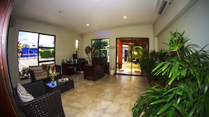 A hotel lobby with a reception desk, seating area, and potted plants. - Hotel Boutique Iguana Verde (Orotina)