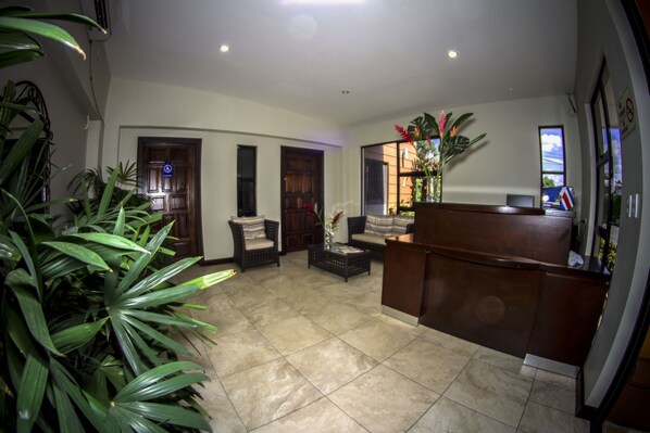 A spacious lobby with a reception desk, seating area, and large windows. - Hotel Boutique Iguana Verde (Orotina)