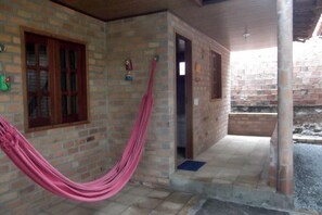 A brick building with a hammock hanging in front, a door, and a window.
