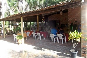 An outdoor patio area with tables and chairs, a brick building, and potted plants.