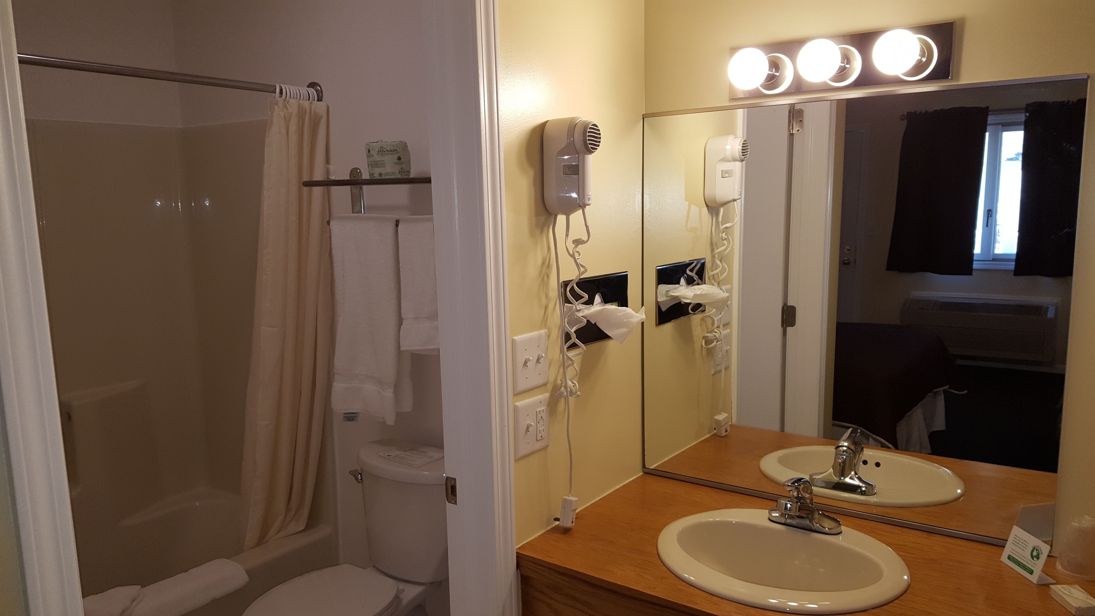 Un bagno con doccia, toilette, lavabo con specchio e lavandino.