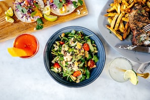 Una comida con tacos, papas fritas, carne a la parrilla y una ensalada.
