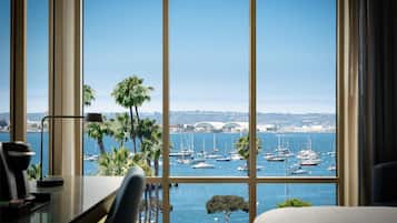 A room with a large window overlooking a marina with boats and a bridge in the distance.