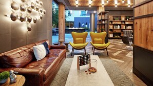 Ein modernes Interieur mit einem Ledersofa, gelben Sesseln, einem Couchtisch und einem Bücherregal.