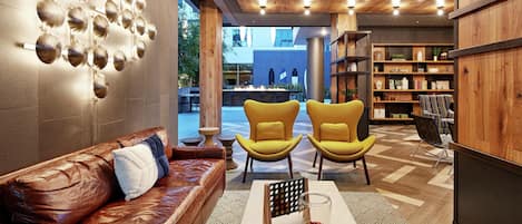 A modern interior with a leather sofa, yellow chairs, a coffee table, and a bookshelf.