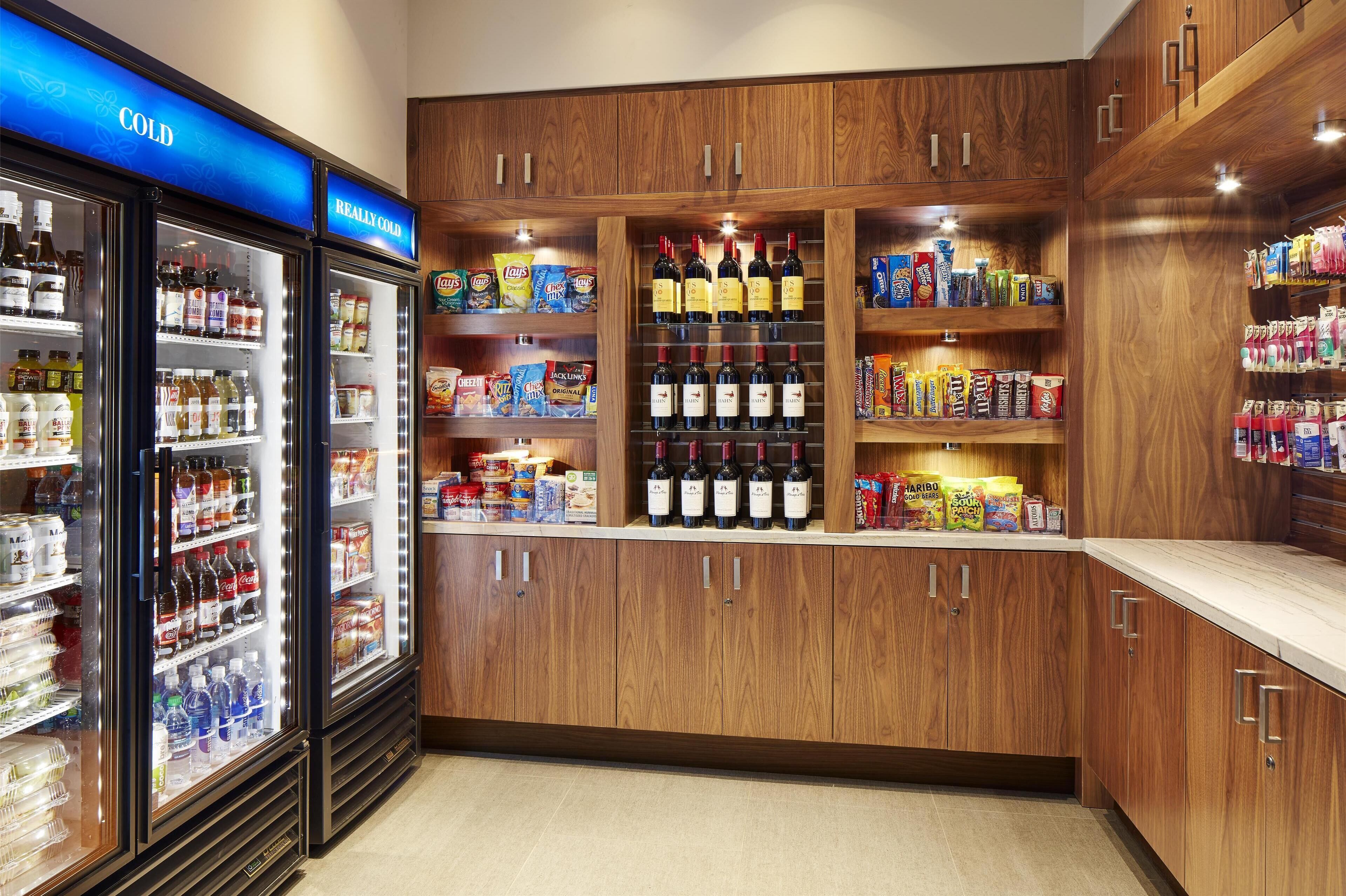 A well-stocked beverage and snack section with refrigerated drinks, wine, and various packaged goods.